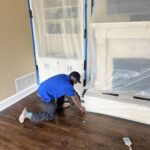 Pro-Craft Restoration technician repairing damaged flooring inside a home.